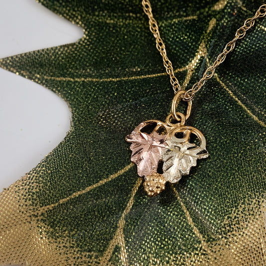 10K yellow gold small double leaf and grape cluster tapered dangle pendant by Landstrom's Black Hills Gold, styled view