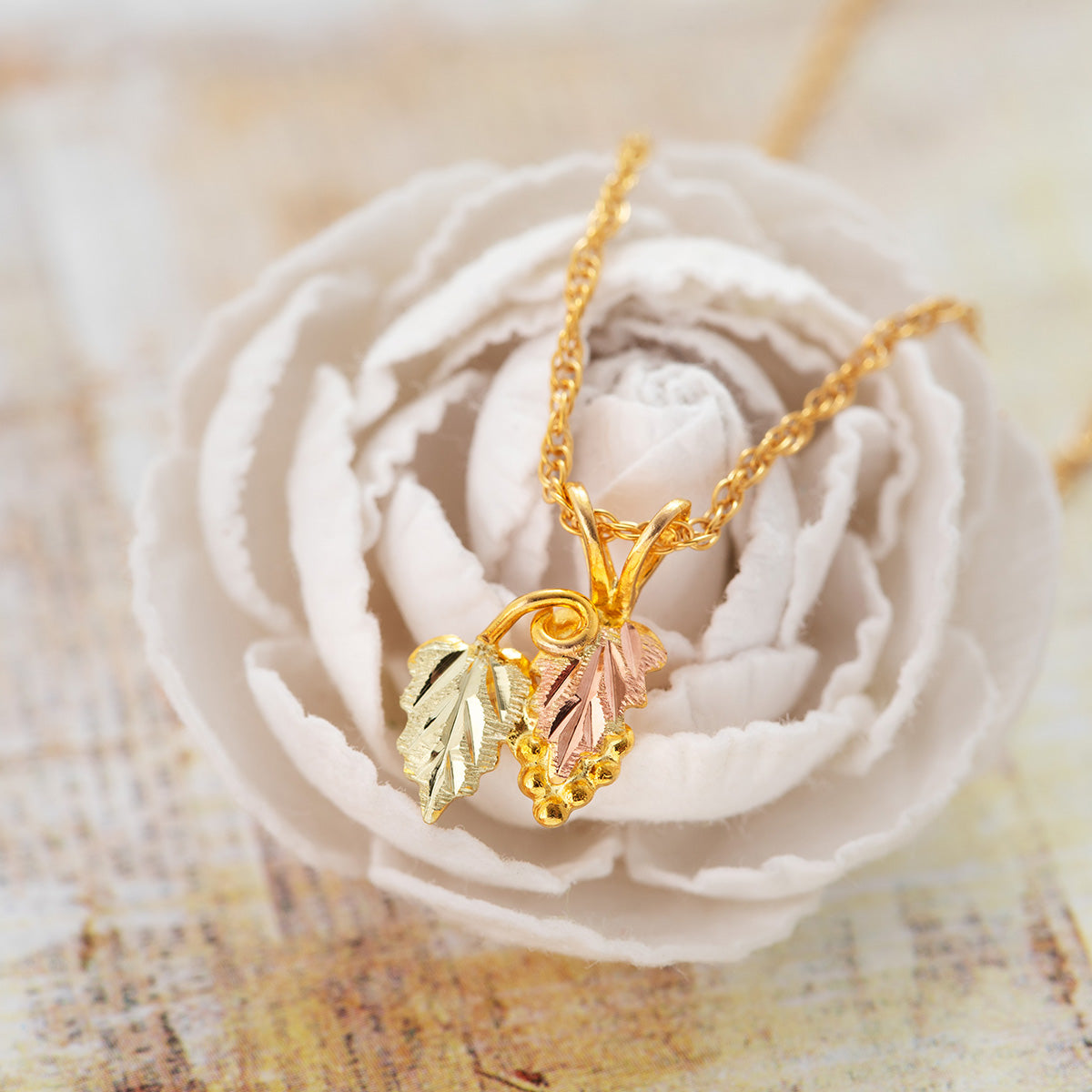 10K yellow gold double leaf and curled vine pendant by Landstrom's Black Hills Gold, styled view