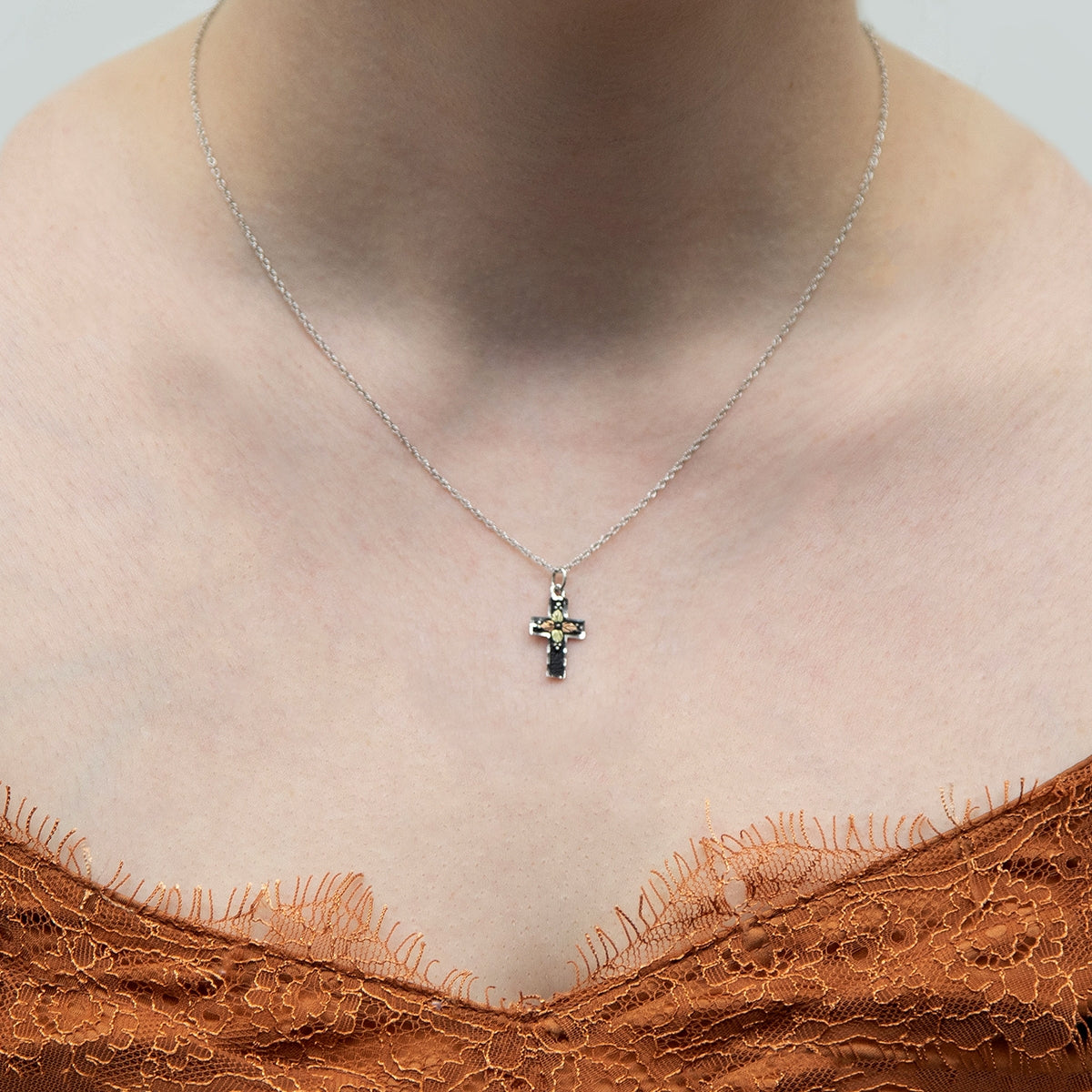 Sterling silver diamond cut edge antiqued cross pendant by Landstrom's Black Hills Gold, shown worn