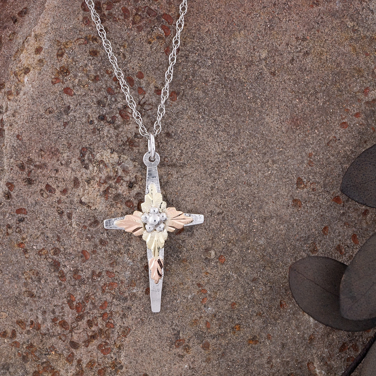 Sterling silver grape cluster center cross pendant by Landstrom's Black Hills Gold, styled view